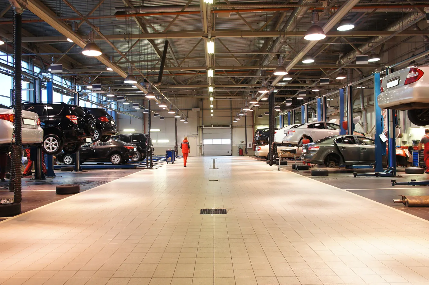 A large vehicle service workshop with cars raised on lifts (general scene)