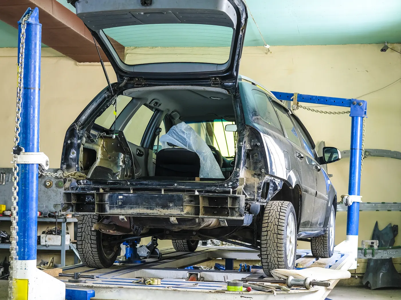 A car clamped on a frame bench with pulling towers in a collision repair shop
